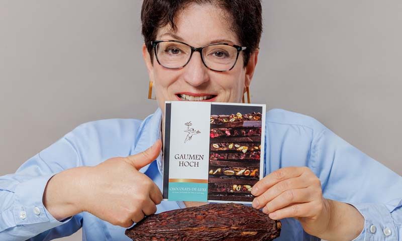 Frau hält eine Broschüre in der Hand in der Größe einer CD auf der steht "Gaumen hoch"