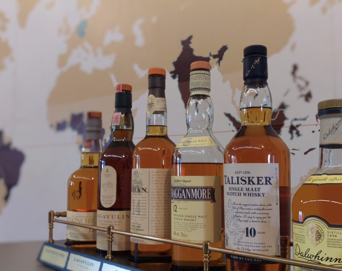 Reihe von Whiskyflaschen vor einer Weltkarte im Hintergrund.
