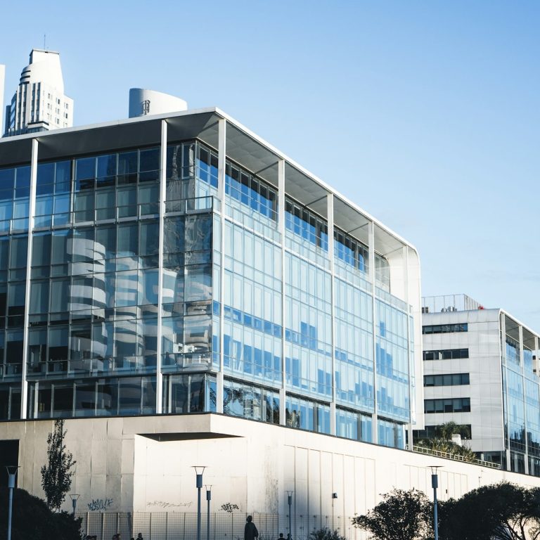 Moderne Büro Blockgebäude mit großen Glasfenstern und klar blauem Himmel.